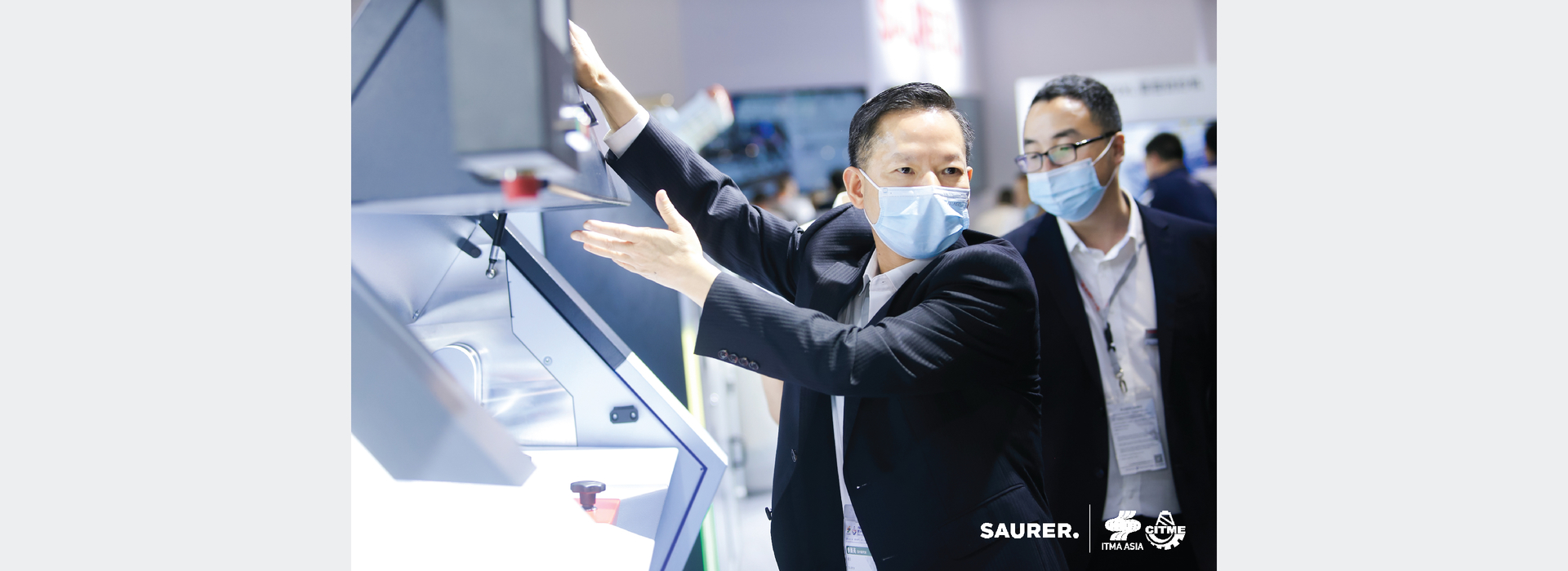 Saurer ITMA Asia employee gesturing at machine